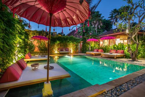 沙努尔PinkPrivate Sanur - for Cool Adults Only的一个带红色遮阳伞和椅子的游泳池以及一座房子