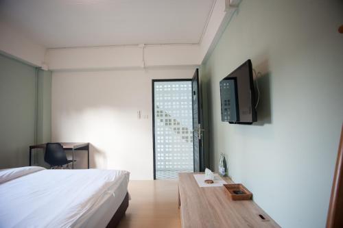 清迈Baan Ploy In的一间卧室配有一张床、一张桌子和一台电视。