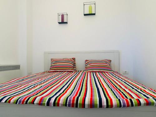 南埃福列Apartament Maria的一张带彩色条纹被子和两个枕头的床