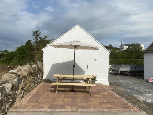 卡文Toddys Cottage & Stables的大楼前带雨伞的野餐桌