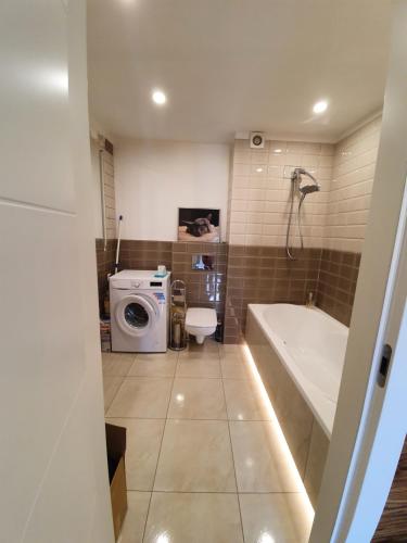 科沙林Apartament Lux的带浴缸和洗衣机的浴室。