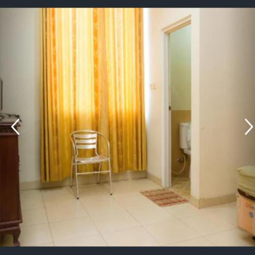 丹戎潘丹Penginapan Sriwijaya的椅子,带窗帘和厕所的房间