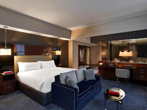 达拉斯焦耳酒店的一间卧室配有一张大床和一张蓝色椅子