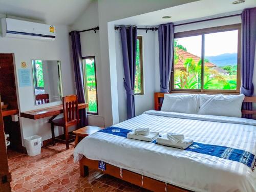 Ban Fai Munวังผา ชาเล่ต์ รีสอร์ท的一间卧室配有一张床、一张书桌和一个窗户。