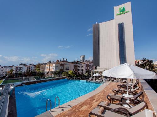 安塔利亚安塔利亚拉拉假日酒店的一座带躺椅的建筑屋顶上的游泳池