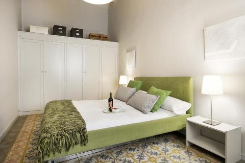 巴塞罗那Ola Living Gaudi的一间卧室配有一张绿色的床,并备有一瓶葡萄酒