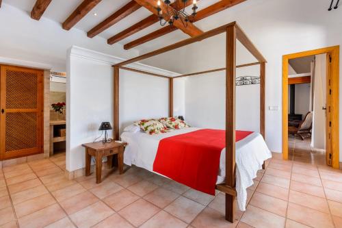 圣胡安包蒂斯塔Can Palau的一间卧室配有一张带红色毯子的天蓬床