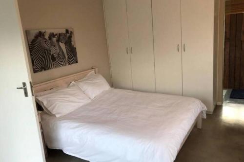 MalgasStaples House - Living The Breede的卧室配有白色的床和墙上的绘画作品