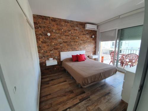 多列毛利诺斯Apartamento Primera Línea de Playa的一间卧室设有砖墙和一张带红色枕头的床
