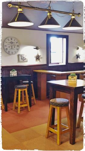 GorronHôtel le Bretagne et Restaurant Le Papillon的厨房配有桌子、凳子和墙上的时钟