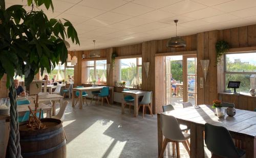 斯希蒙尼克奥赫Strandhotel Om de Noord的一间设有桌椅和盆栽的餐厅