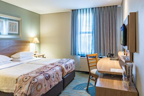 鲁德普特Town Lodge Roodepoort的酒店客房设有一张大床和一张书桌。