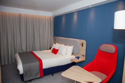 卡迪夫卡迪夫湾智选假日酒店的酒店客房,配有一张床和一张红色椅子