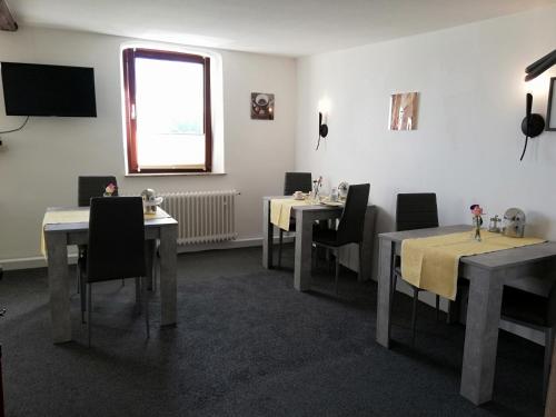 勒沃库森Pension Riverside in Leverkusen Hitdorf am Rhein - Zentral an der A1 und 59的一间带桌椅的用餐室和窗户。