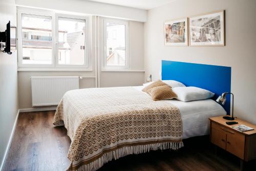 科尔马LE 19 KLEBER climatisé的一间卧室配有一张带蓝色床头板的床和两个窗户