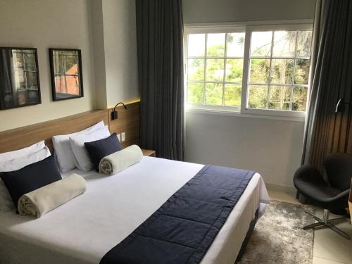 伊泰帕瓦Flat Itaipava - Granja Brasil的一间卧室设有一张大床和一个窗户。