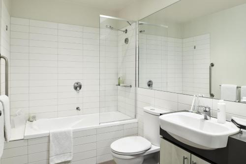 墨尔本Punthill Essendon的白色的浴室设有浴缸、卫生间和水槽。