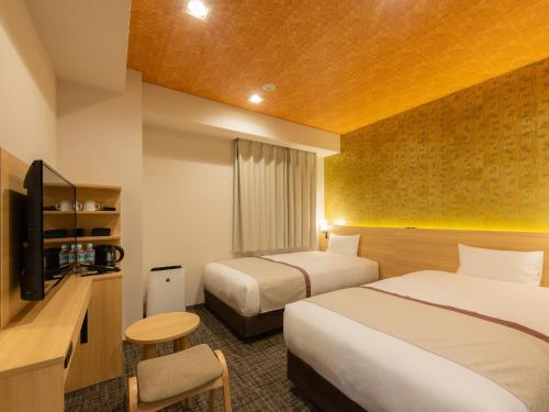 东京Tosei Hotel Cocone Asakusa Kuramae的酒店客房设有两张床和电视。