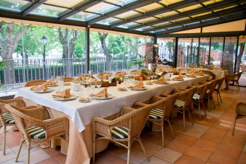 圣洛伦索-德埃斯科里亚尔Hospedium Hotel Los Lanceros的长长的用餐室配有长桌子和椅子