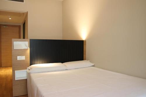 卡塞雷斯阿尔坎塔拉酒店的一间卧室配有一张白色的床和黑色床头板