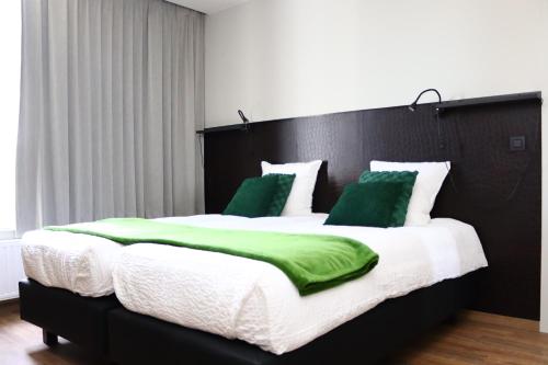 伊普尔Revelatio, dé logies的一张配有绿色和白色毯子及枕头的大床