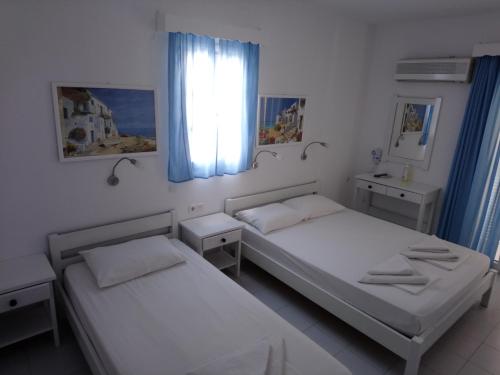 安迪帕罗斯岛Nicolas Antiparos的一间卧室设有两张床,窗户配有蓝色窗帘