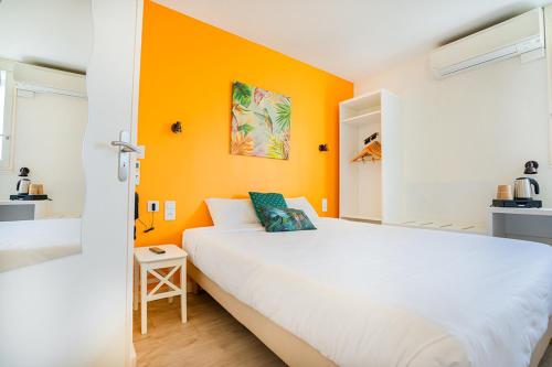 勒斯奎斯特勒Logis Hôtel Le Rialto的卧室配有白色的床和橙色的墙壁