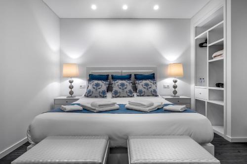 佩尼契Ilheu 25 Peniche House的白色卧室配有一张带蓝色枕头的大床