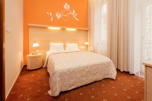 卡罗维发利金星酒店的一间卧室配有一张带橙色墙壁的大床