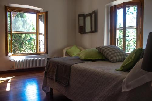 皮斯托亚RESIDENZA LE CICOGNE的一间卧室配有带绿色枕头的床和2个窗户