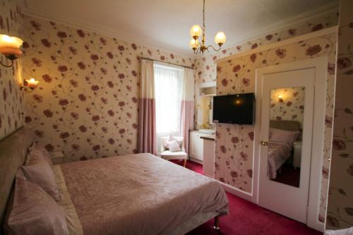 珀斯度纳兰旅馆的卧室配有一张床,墙上配有电视。
