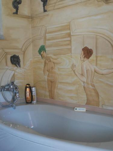 卢戈Antico Casale dei Sogni agriturismo的浴室配有浴缸,墙上挂有绘画作品