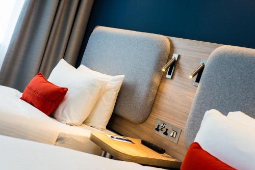 马瑟韦尔快捷假日斯特拉思克莱德公园M74高速公路5号岔口酒店的酒店的客房 - 带红色和白色枕头的床