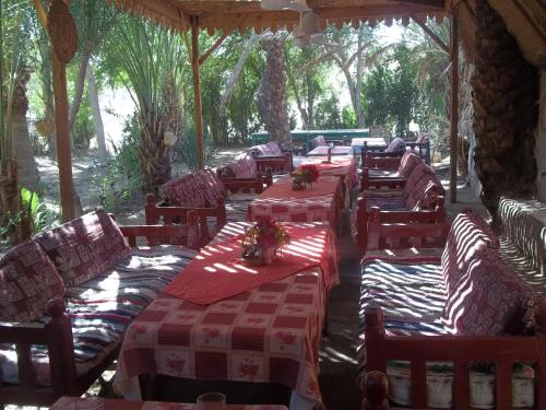 卢克索努尔埃尔格鲁纳酒店的餐厅设有桌椅,配有红色和白色的桌布