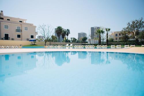 阿尔沃尔Dunas do Alvor - Budget的一座带椅子的大型游泳池和一座建筑