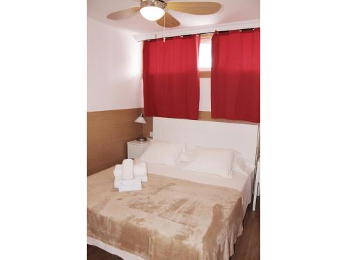 英格兰海滩Aloe Friendly Holiday Home的一间卧室配有一张带红色窗帘的床和吊扇