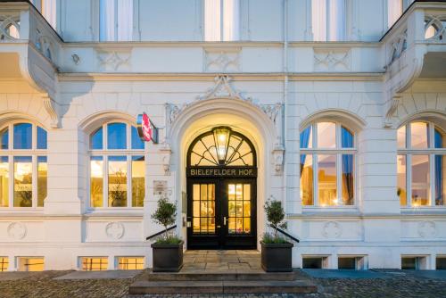 比勒费尔德Steigenberger Hotel Bielefelder Hof的一座白色的大建筑,设有黑色的门