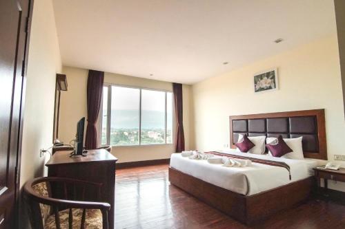巴色爱侣湾大酒店 的一间卧室配有一张床、一张书桌和一个窗户。