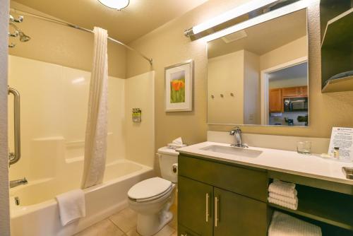 梅德福梅德福烛木套房酒店的浴室配有盥洗盆、卫生间和浴缸。