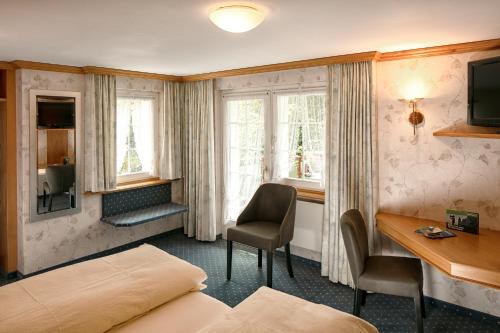韦斯巴德Hotel Alpenblick的酒店客房设有一张床、一张书桌和窗户。