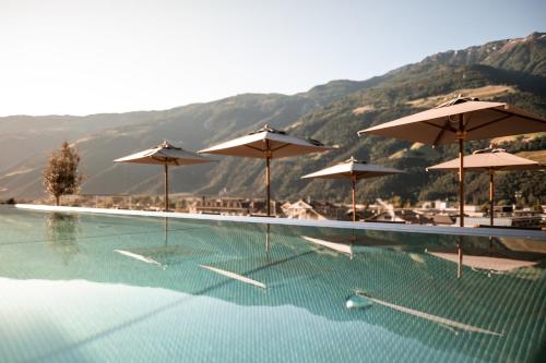 纳图尔诺Sonnen Resort的一个带遮阳伞和桌椅的游泳池