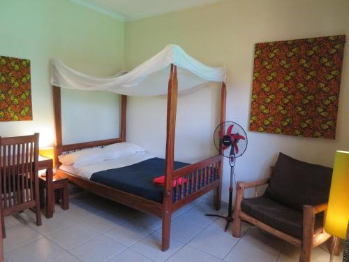 金贾Bikeventures House Uganda的一间卧室配有一张天蓬床和一把椅子