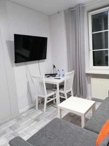 奥尔什丁Apartamenty u Szwejka Stare Miasto的客厅配有桌子和墙上的电视