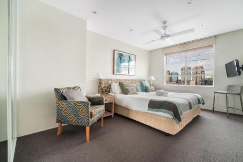 悉尼Harbourside #76的卧室配有床、椅子和窗户。
