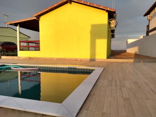 蒙蒂达斯加梅莱拉斯Chalés Serra Monte的一座黄色的房子,前面有一个游泳池