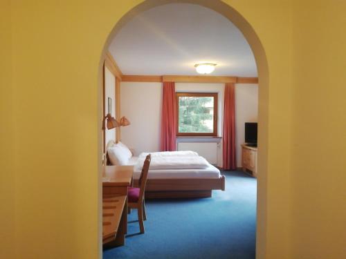安泰塞尔瓦·迪·梅佐体育威尔德盖尔酒店的一间卧室配有一张床、一张书桌和一个窗户。