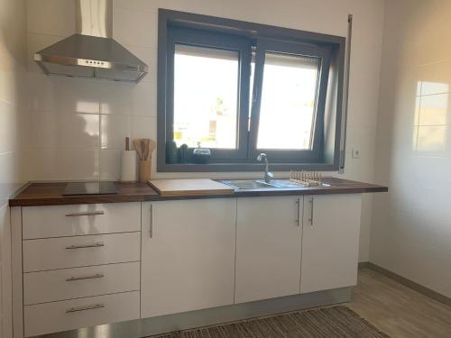 欧瓦AMARÉ Lodge®的厨房配有白色橱柜、水槽和窗户。