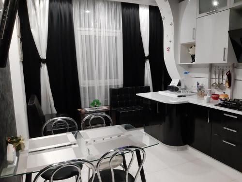 敖德萨Маршала Малиновського 18 б 12 Жемчужина квартира的厨房配有白色的柜台、黑色的窗帘和椅子