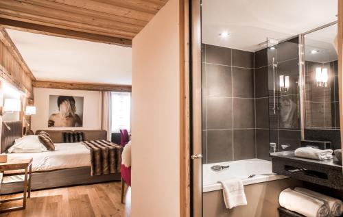 拉克吕萨爱心村社酒店的一间卧室配有一张床,浴室设有淋浴。