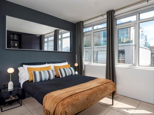 伦敦D8 - Hoxton Square Penthouse的一间卧室配有一张带黄色枕头的床和窗户。